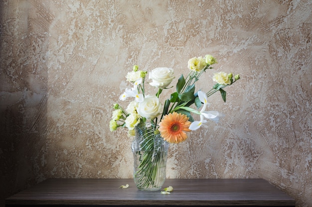 Bouquet dans un vase en verre sur une table dans un mur d'arrière-plan