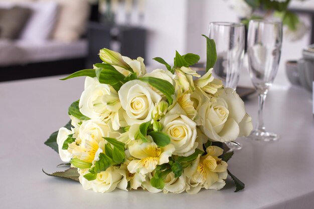 Photo bouquet délicat festif avec des roses légères sur la table sur fond de verres en verre