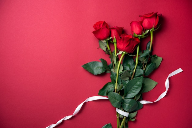 Photo bouquet délicat de roses rouges allongé sur fond rouge