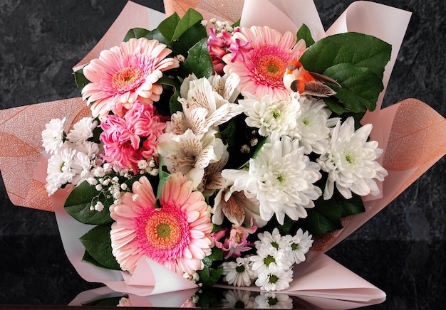 Photo bouquet de différentes fleurs en tons roses et blancs sur un fond sombre