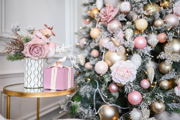 Bouquet de fêtes du Nouvel An dans un vase, un coffret cadeau rose sur la table de chevet en verre