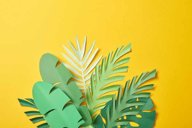 Bouquet de feuilles de palmier vert exotique coupées en papier sur fond jaune avec espace de copie