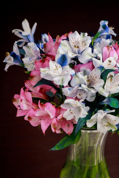 Bouquet de fleurs d'alstroemerias roses et bleues dans un vase en verre.