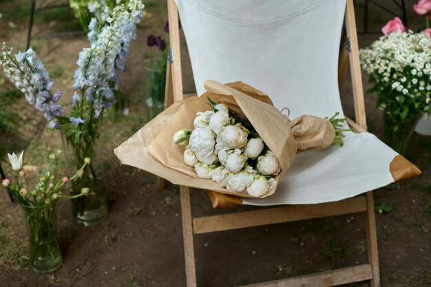 Bouquet de fleurs blanches sur une chaise dans le jardin sur fond de fleurs dans des vases