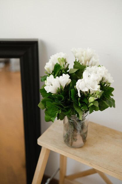 Bouquet de fleurs blanches dans un vase en verre sur une étagère en bois Le printemps est dans la ville et dans l'âme