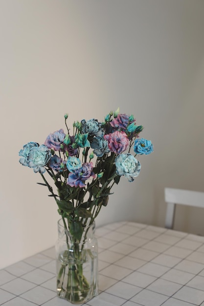 bouquet de fleurs bleues et violettes dans un bocal sur la table dans une pièce ensoleillée décoration minimale