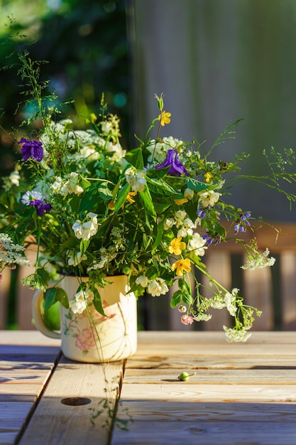 Bouquet de fleurs des champs sur une table de jardin éclairée par les rayons du soleil