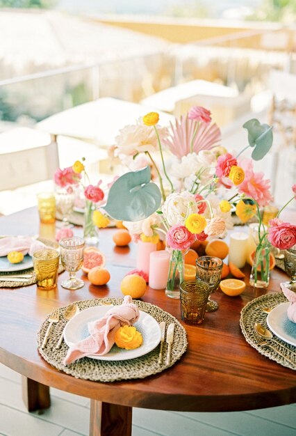 Un bouquet de fleurs colorées se tient sur une table avec des bougies et des raisins secs et des oranges.