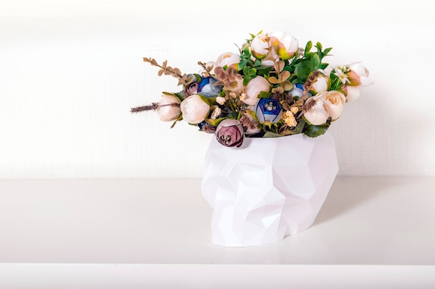 Bouquet de fleurs en crâne low poly sur fond clair. Décor à la maison dans un style vanité minimal. Concept créatif pour les vacances d'Halloween.