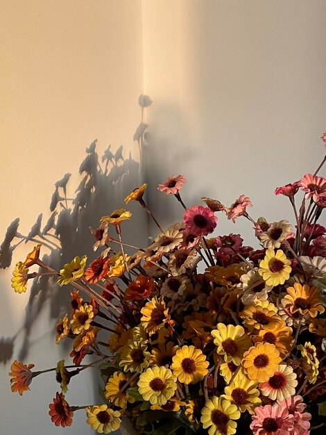 Photo un bouquet de fleurs dans un coin d'une pièce avec une ombre.