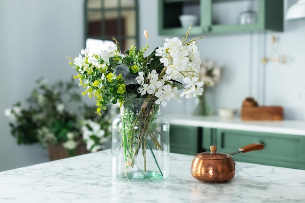 Bouquet de fleurs dans un vase en verre et turc avec café dans la table de la cuisine.