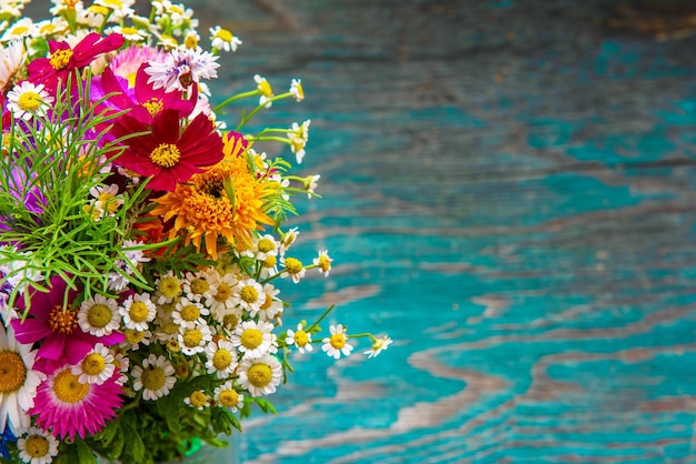 Bouquet de fleurs fraîches d'été sur le bureau grunge en bois bleu. Conception de cartes de vœux de Pâques, cartes postales de vacances, invitation dans un style rustique éco hipster vintage avec espace de copie