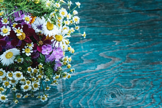 Bouquet de fleurs fraîches d'été sur le bureau grunge en bois bleu. Conception de cartes de vœux de Pâques, cartes postales de vacances, invitation dans un style rustique éco hipster vintage avec espace de copie