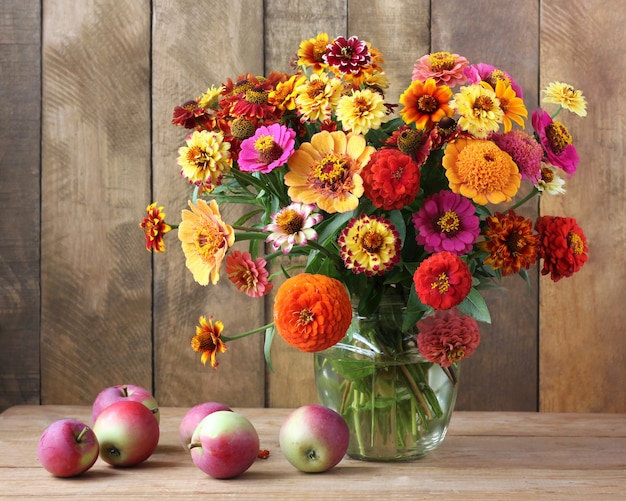 Bouquet de fleurs de jardin et de pommes sur une table en bois.