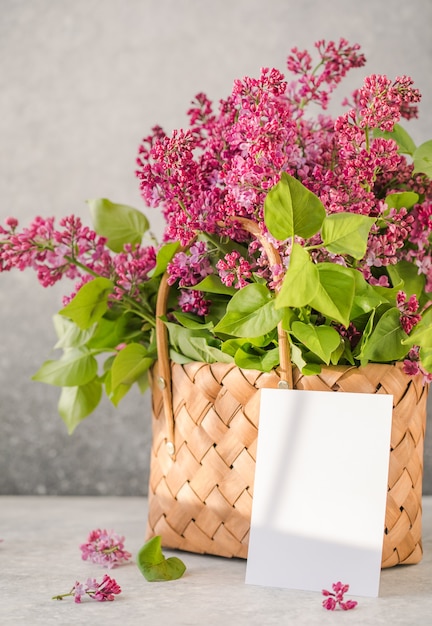 Bouquet de fleurs lilas colorées avec une carte dans un panier en osier