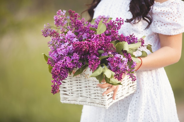 Bouquet de fleurs lilas dans les mains de la dame de yong. Fleurs d'été dans le panier