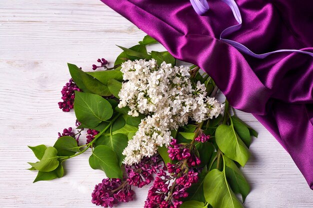 Bouquet de fleurs lilas et draperie violette sur fond blanc c