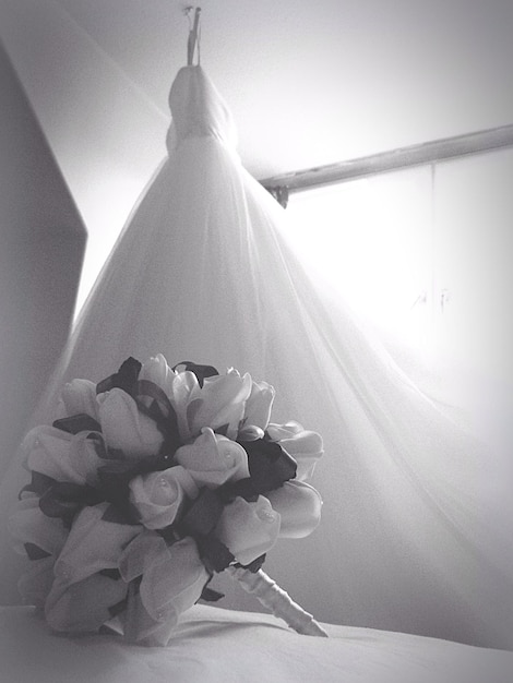 Photo bouquet de fleurs sur le lit par la robe de mariée