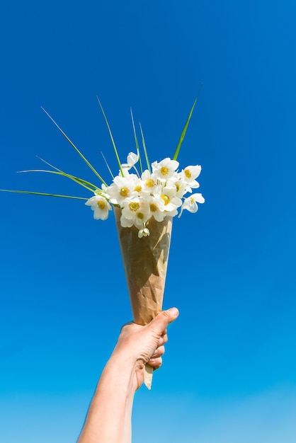 Bouquet de fleurs à la main contre un ciel bleu vif