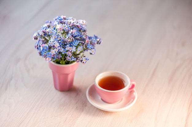 Un bouquet de fleurs myosotis sur une table avec une tasse de thé. Fond de vacances, espace de copie, mise au point douce. Fête des mères, concept d'anniversaire.