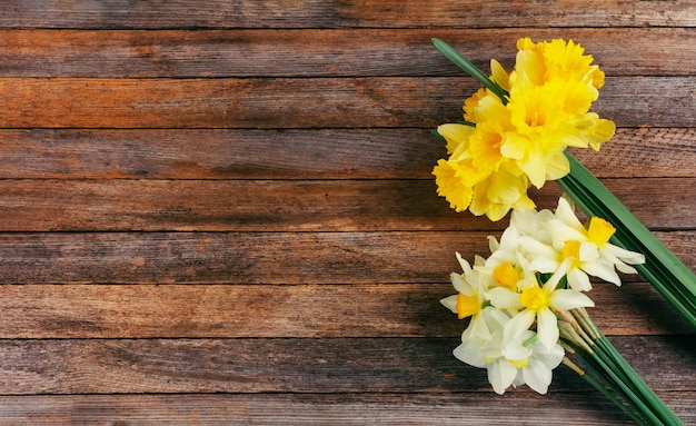 Un bouquet de fleurs de narcisse blanc et jaune sur un fond en bois marron avec un espace de copie