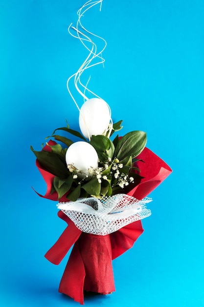 Photo un bouquet de fleurs avec des oeufs de pâques au lieu de fleurs sur fond bleu