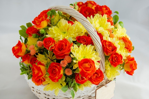 Bouquet de fleurs panier en osier avec roses rouges et chrysanthèmes jaunes dans une boîte cadeau