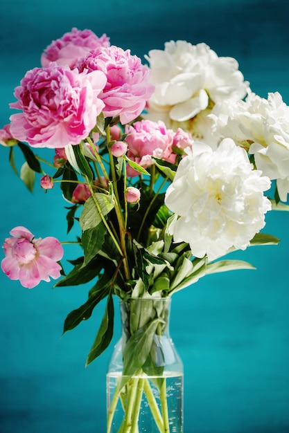 Photo bouquet de fleurs de pivoines naturelles roses dans un vase sur fond turquoise fleurs de printemps et d'été