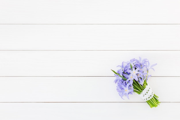 Bouquet de fleurs printanières décorées de dentelle sur un mur en bois blanc. Vue de dessus, espace copie