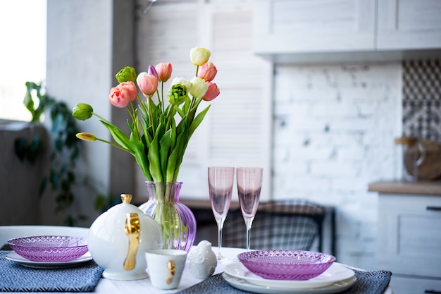 Bouquet de fleurs de printemps avec une belle vaisselle en verre violet dans la cuisine