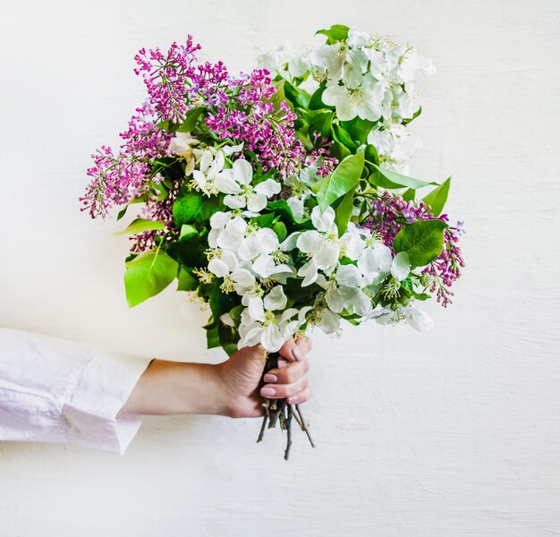 Bouquet de fleurs de printemps dans une main féminine sur fond blanc