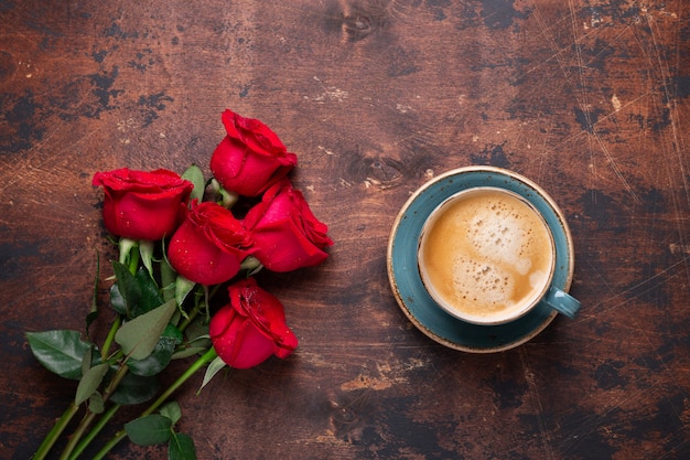 Bouquet de fleurs rose rouge et tasse de café sur fond en bois