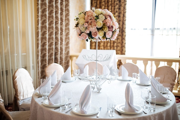 Bouquet de fleurs rose tendre sur la table de banquet servi avec des murs blancs