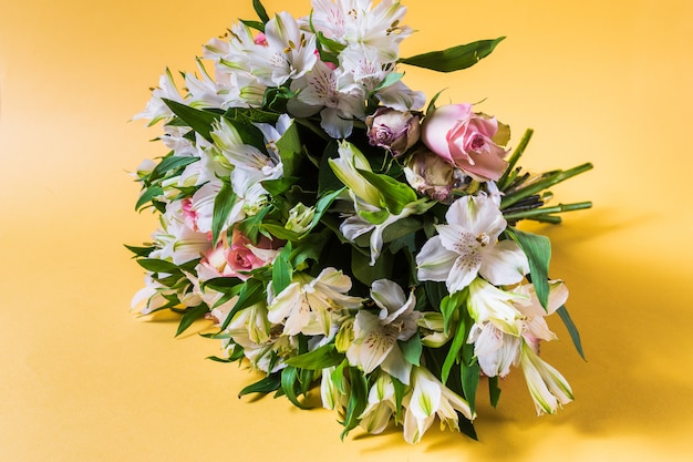 Bouquet de fleurs roses et blanches sur fond jaune.