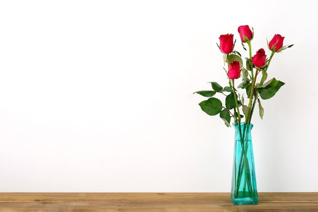 Bouquet de fleurs de roses rouges dans un vase vert sur fond blanc