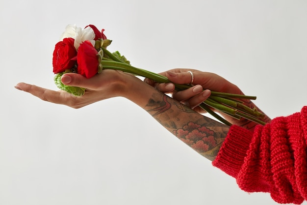 Un Bouquet De Fleurs Rouges, Blanches Et Vertes Dans Les Mains D'une Fille Tatouée Sur Les Mains. Fête Des Mères. La Saint-valentin.