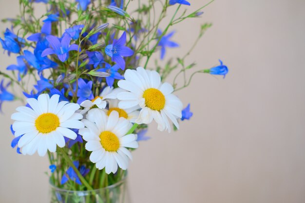 Un bouquet de fleurs sauvages dans un vase. Camomille et cloches dans un bouquet, à la maison.