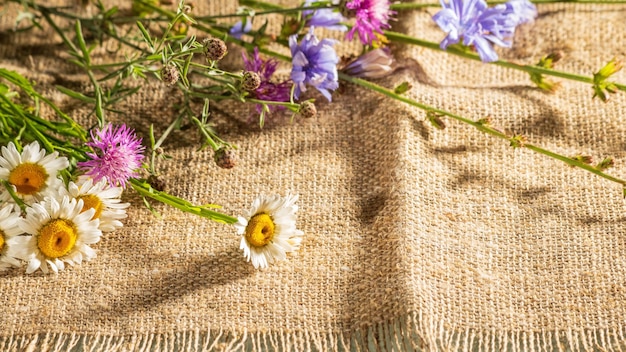 Un bouquet de fleurs sauvages simples se trouve sur une serviette en toile de jute