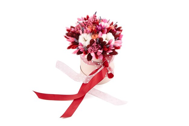 Bouquet de fleurs séchées avec des herbes dans une boîte à chapeau ronde rose isolé sur fond blanc