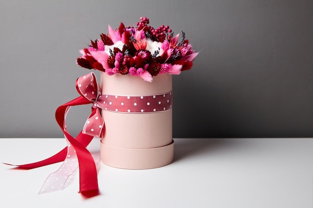 Bouquet de fleurs séchées avec des herbes dans une boîte à chapeau ronde rose