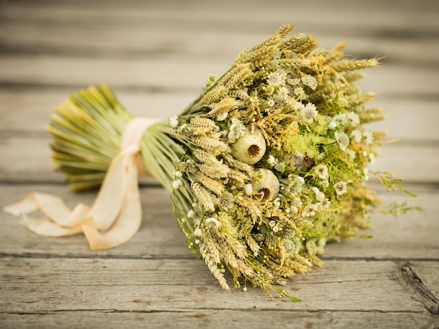 Bouquet de fleurs séchées. Nature morte aux épis de blé et fleurs sauvages jaunes et blanches sur fond de bois