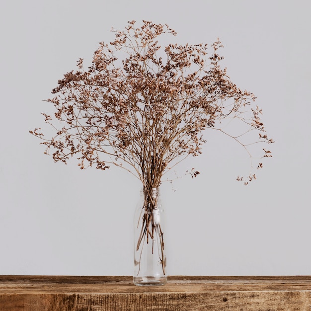 Bouquet de fleurs sèches dans une bouteille en verre sur une table en bois sur fond gris