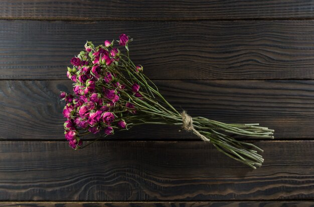 Bouquet de fleurs sèches avec un ruban sur la surface en bois sombre.