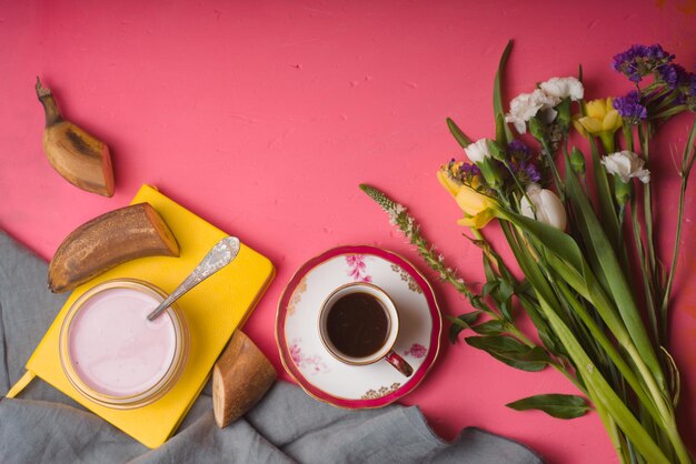 Bouquet de fleurs tasse de yaourt de café sur une table rose