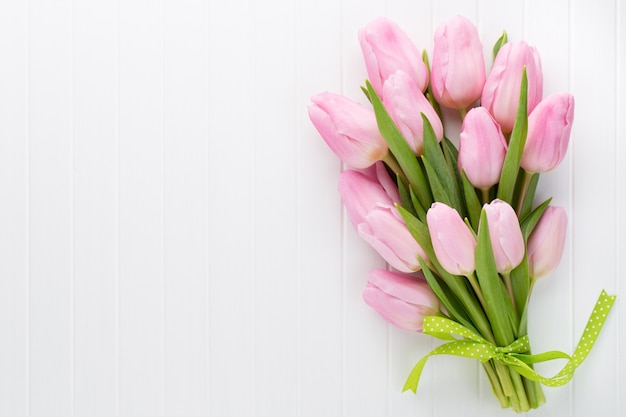 Bouquet de fleurs de tulipes roses fraîches sur une étagère devant un mur en bois.