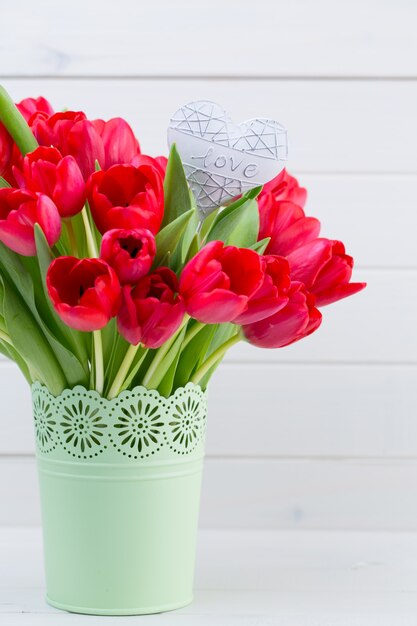 Bouquet de fleurs de tulipes rouges fraîches sur étagère en face de mur en bois