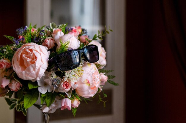 Un bouquet de fleurs et de verres sur une table dans une pièce sombre.