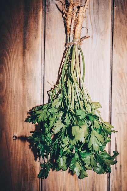 Un bouquet frais de persil suspendu à une corde sur un fond de bois