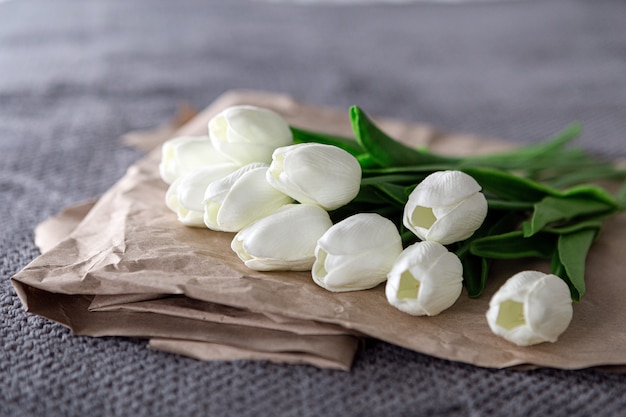 Bouquet frais de tulipes blanches sur papier recyclé sur fond gris
