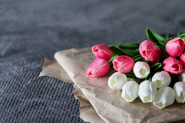 Bouquet frais de tulipes blanches et roses sur du papier recyclé sur fond gris